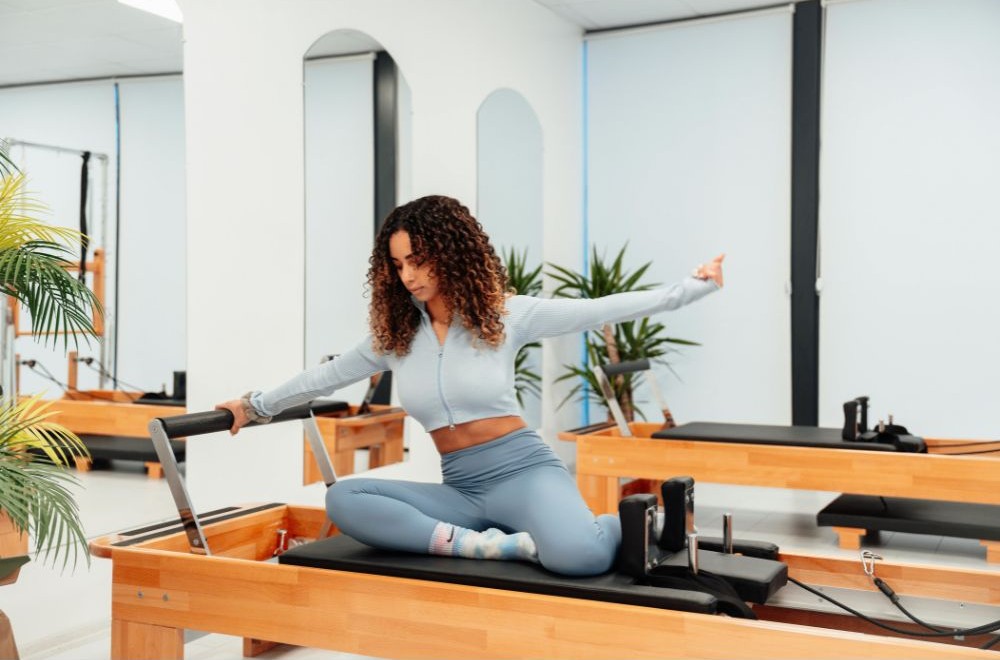 Woman doing a pilates reformer exercise in a bright studio, supporting muscle recovery and endurance
