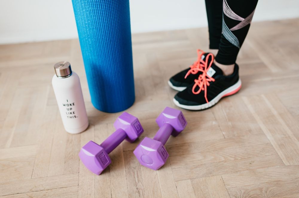 Yoga mat, water bottle, dumbbells, and sneakers laid out for a home workout, representing an active lifestyle supported by matcha