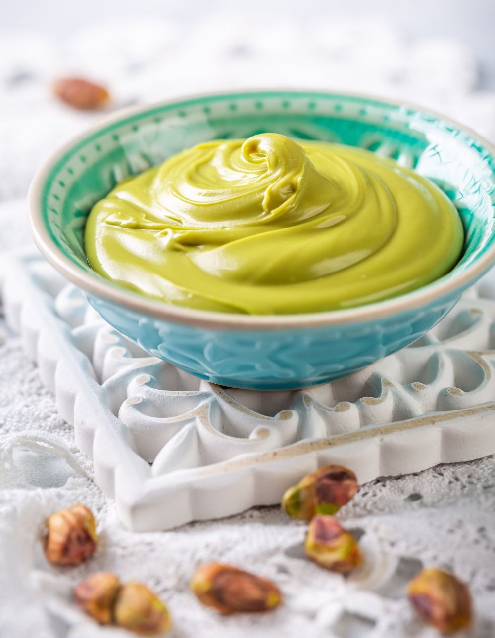 Bowl of smooth pistachio cream surrounded by shelled pistachios