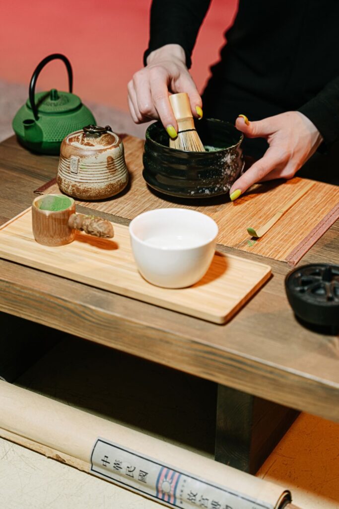 Traditional matcha tea ceremony set with a white bowl, bamboo scoop, and matcha powder on a wooden tray