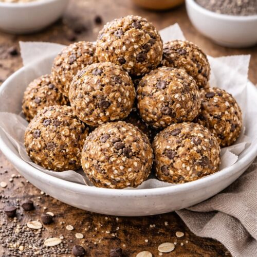 Homemade energy balls made with oats, peanut butter, and chia seeds, with ingredient bowls in the background