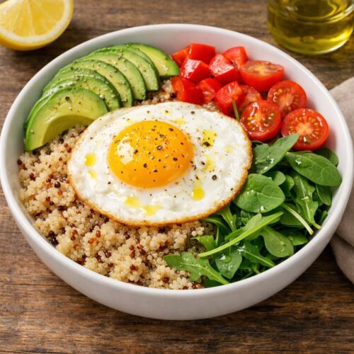 Fried egg quinoa bowl with avocado, cherry tomatoes, bell pepper, and arugula