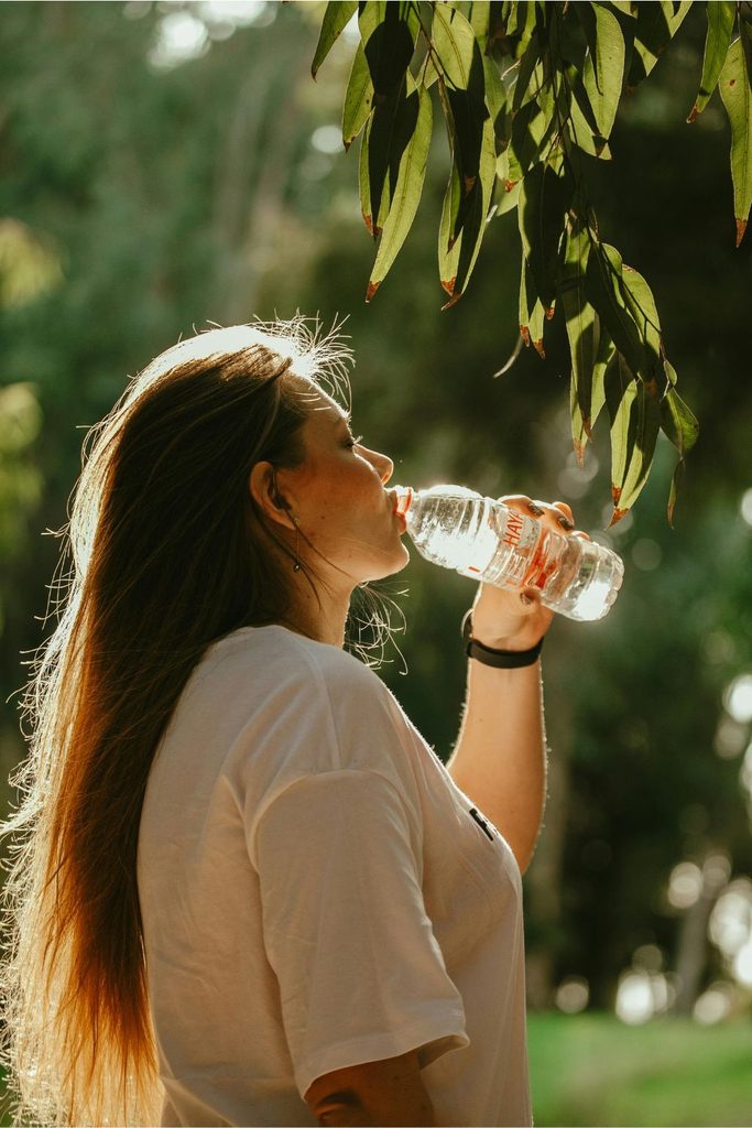 Woman drinking bottled water outdoors, highlighting bottled water's environmental impact