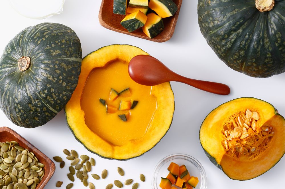 Kabocha pumpkin soup in a hollowed pumpkin bowl with pumpkin seeds on the side
