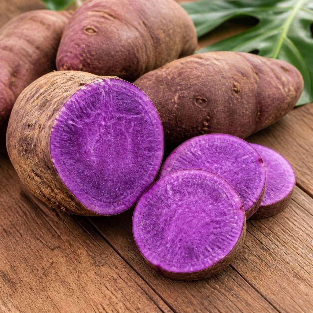 Whole and halved purple ube tubers on a wooden table